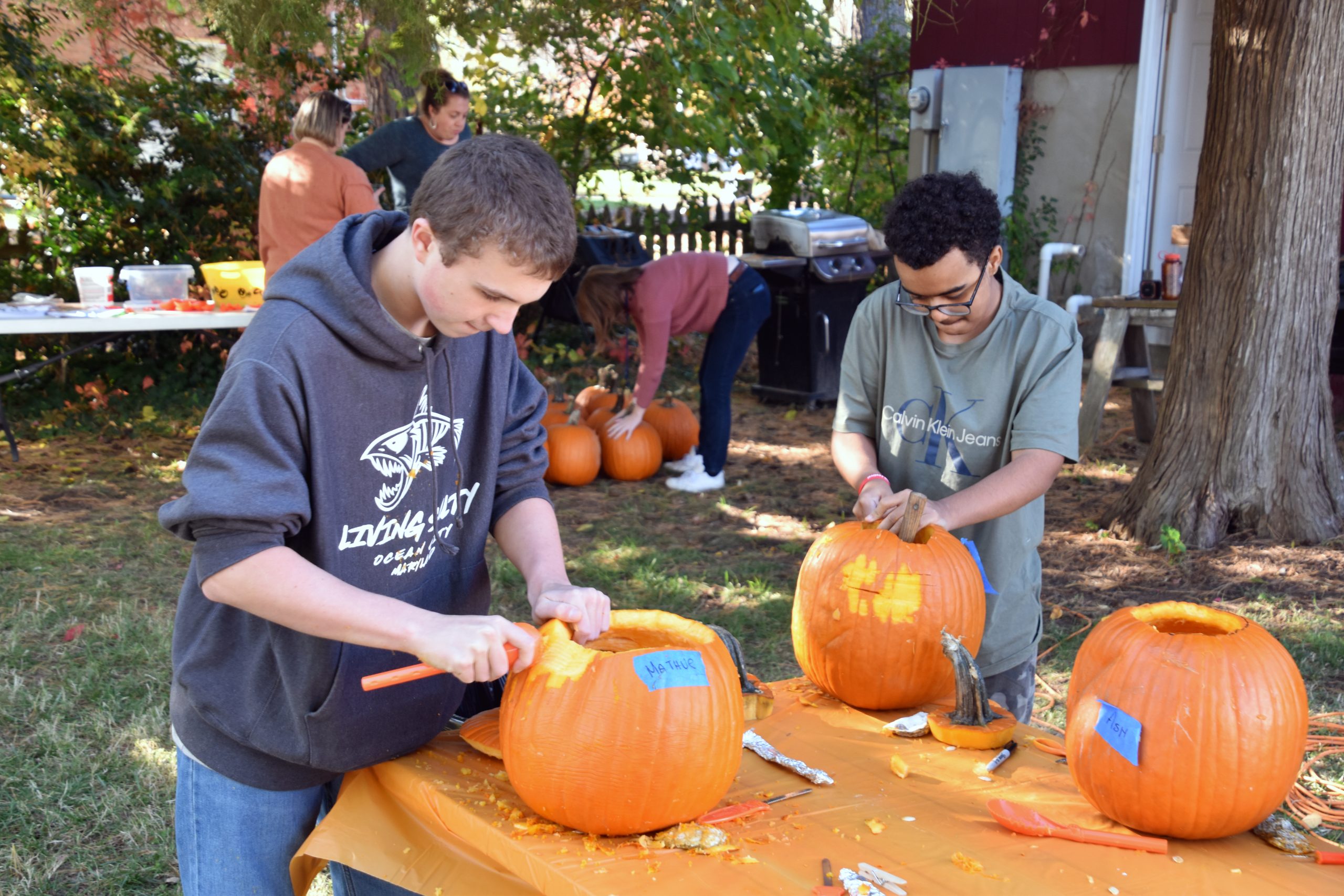 Two young people carve pumpkins.