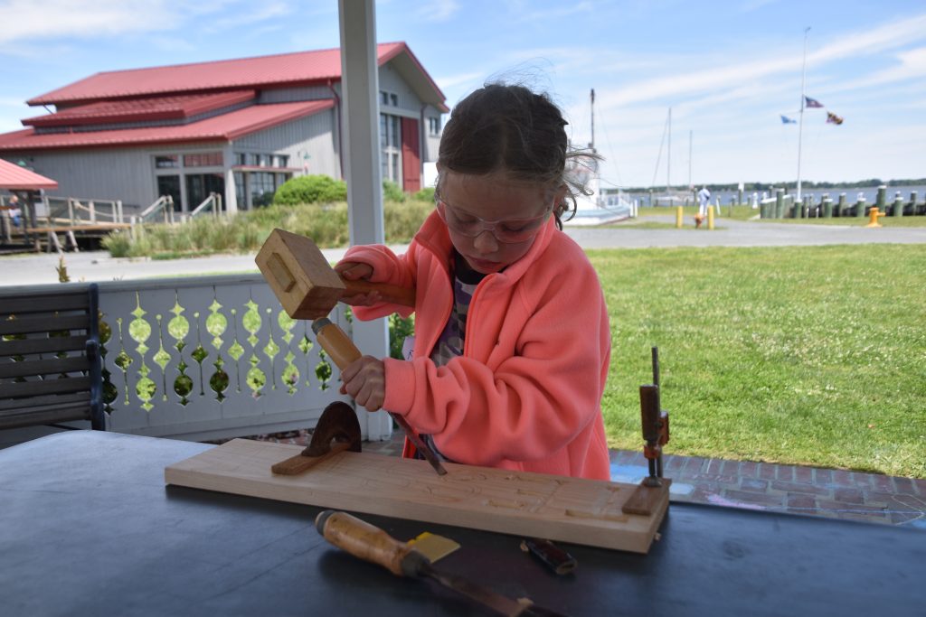 A young girl carves her name.